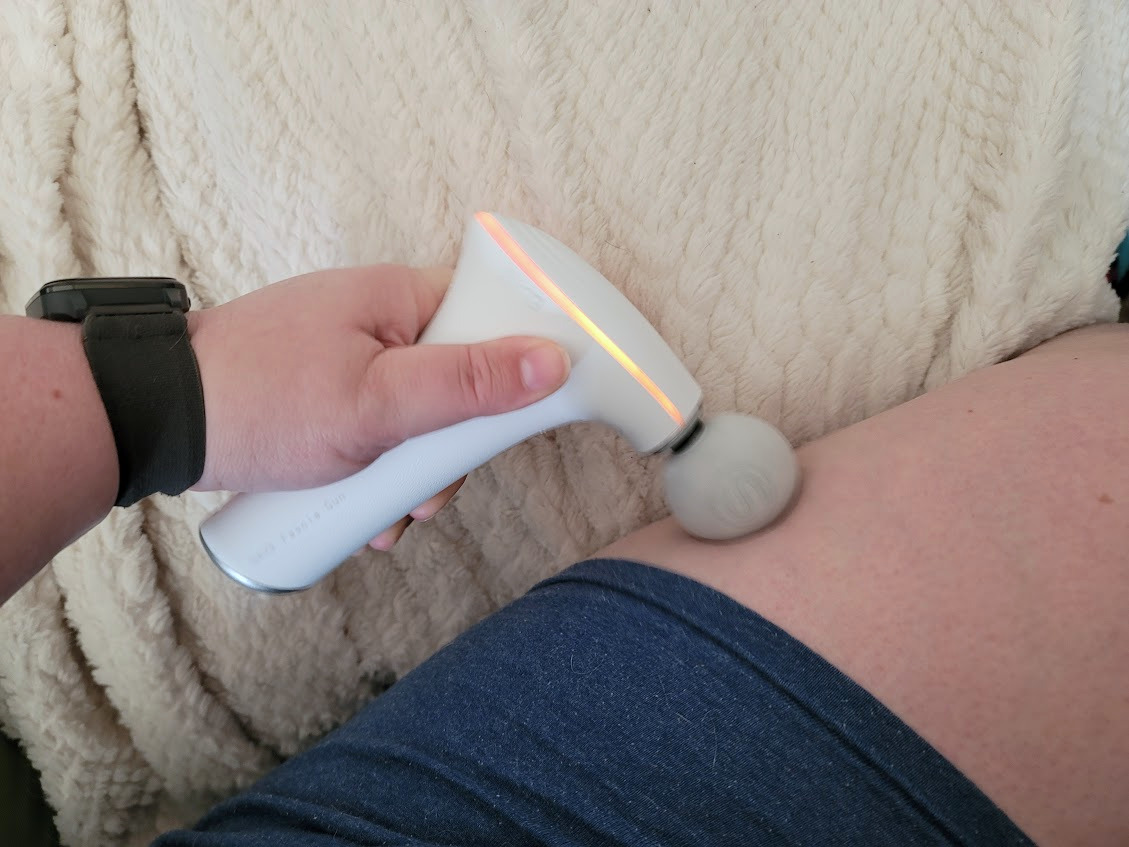 SKG F5 Massage Gun in use on a thigh